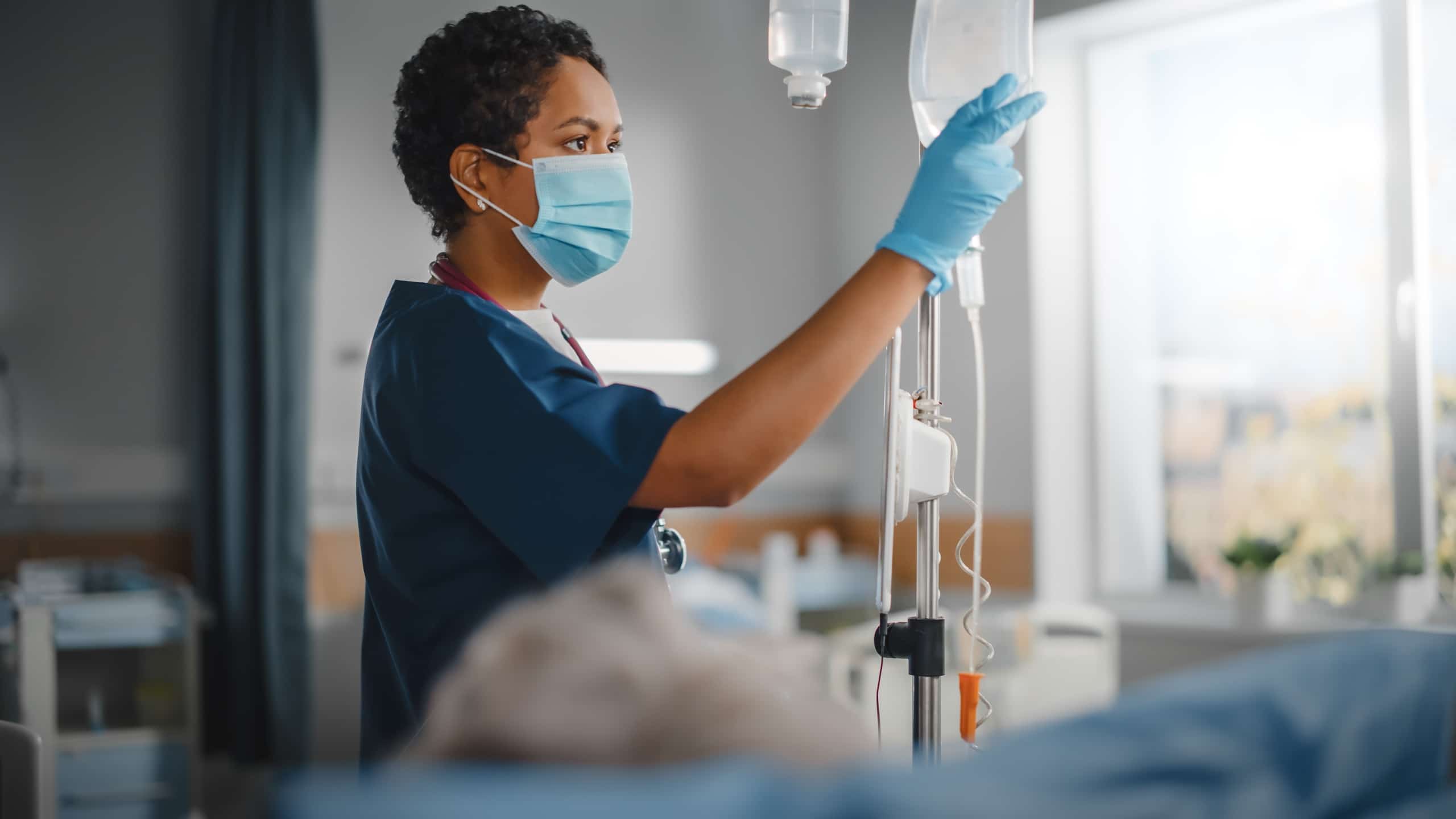 Masked nurse checking a patient's IV