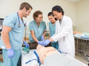 Asian instructor with students using a medical mannequin