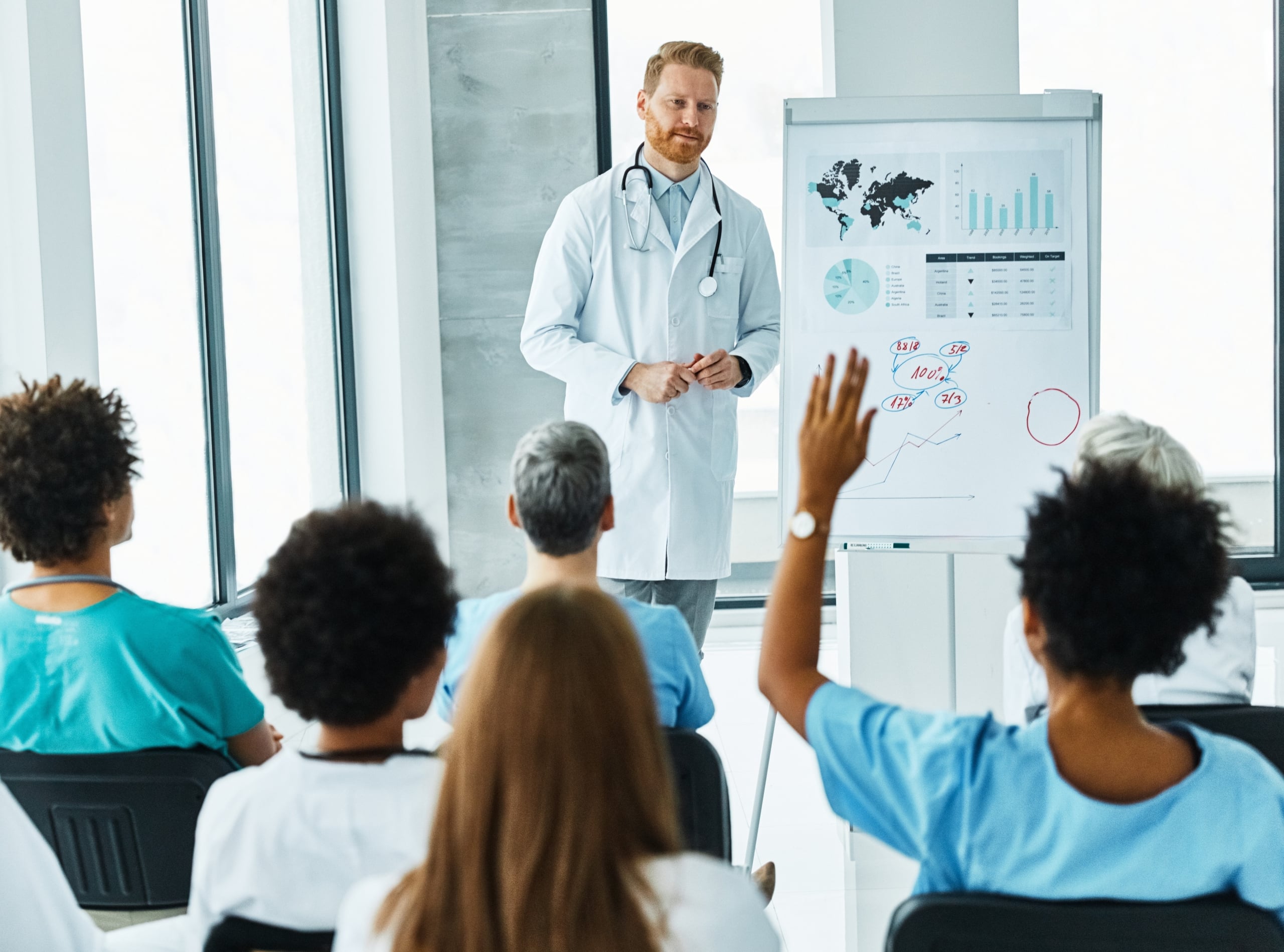 Medical professor standing in front of students with raised hands