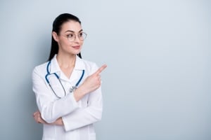 Professional nurse pointing to the side against a solid backdrop