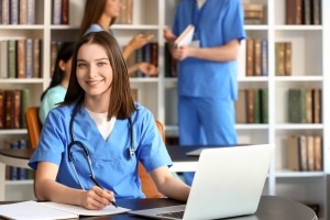 Nursing student using a laptop in a school library