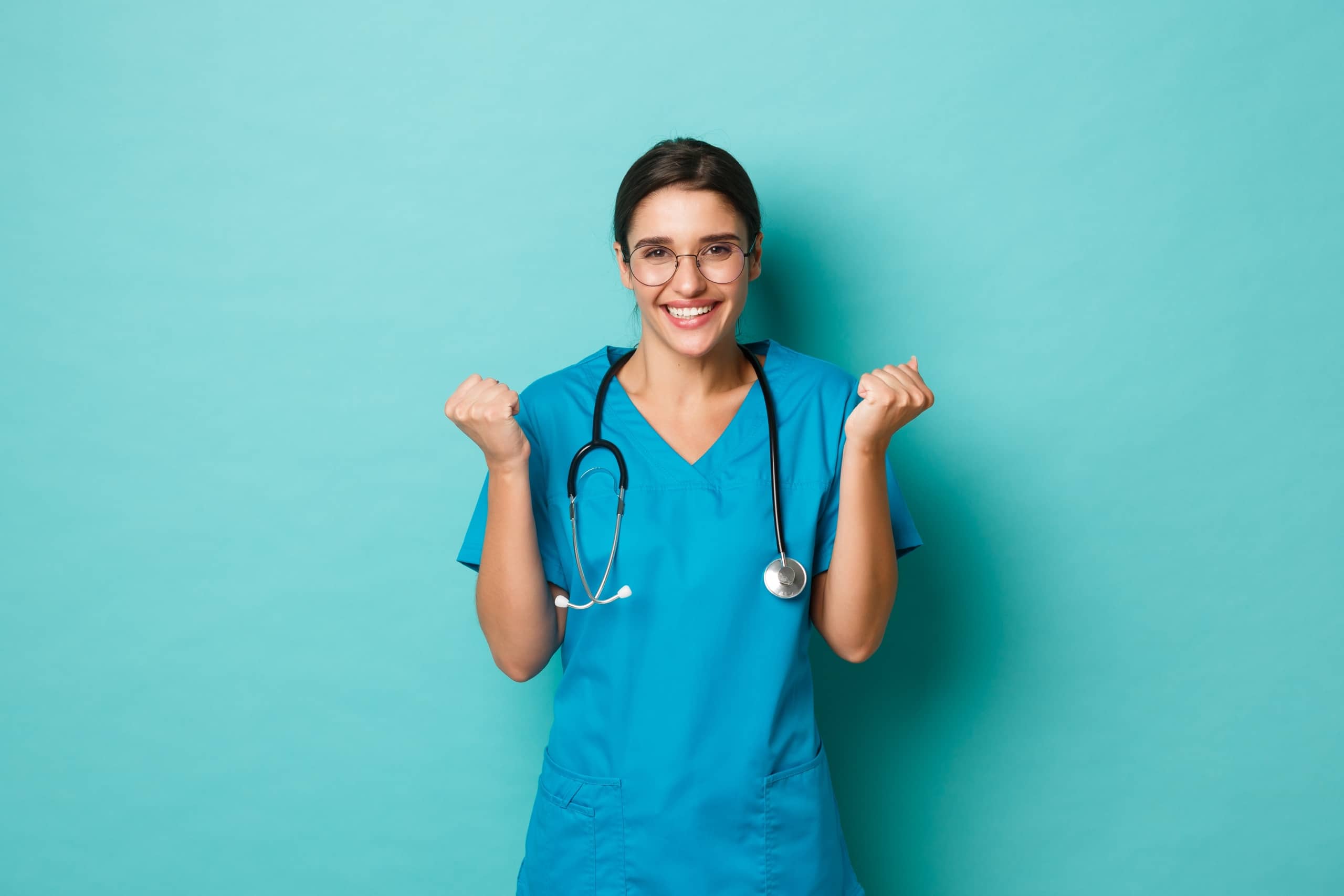 Smiling nurse in scrubs against a solid background