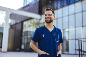 Joyful male nurse standing outside a hospital