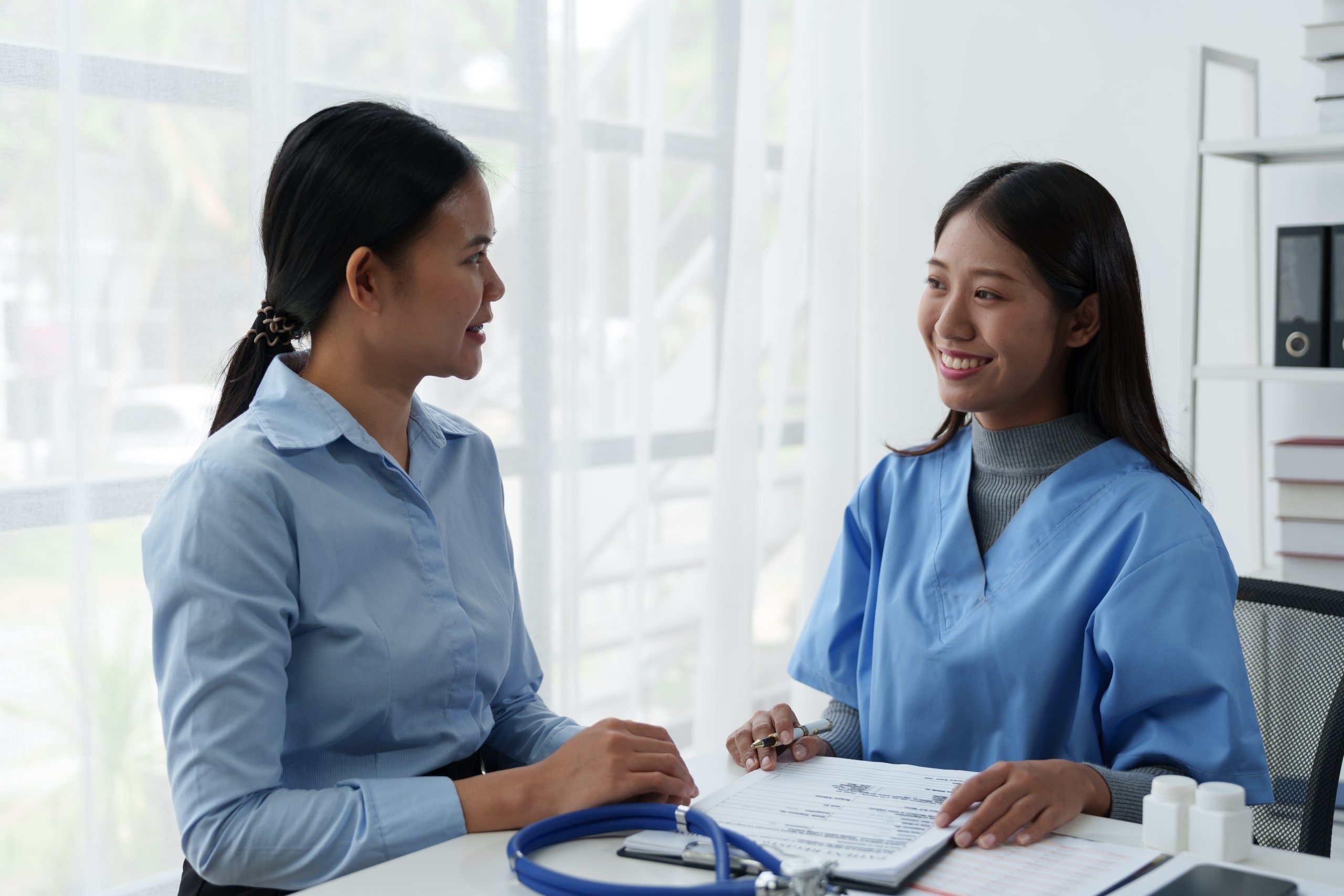 Asian nurse speaking with a female patient