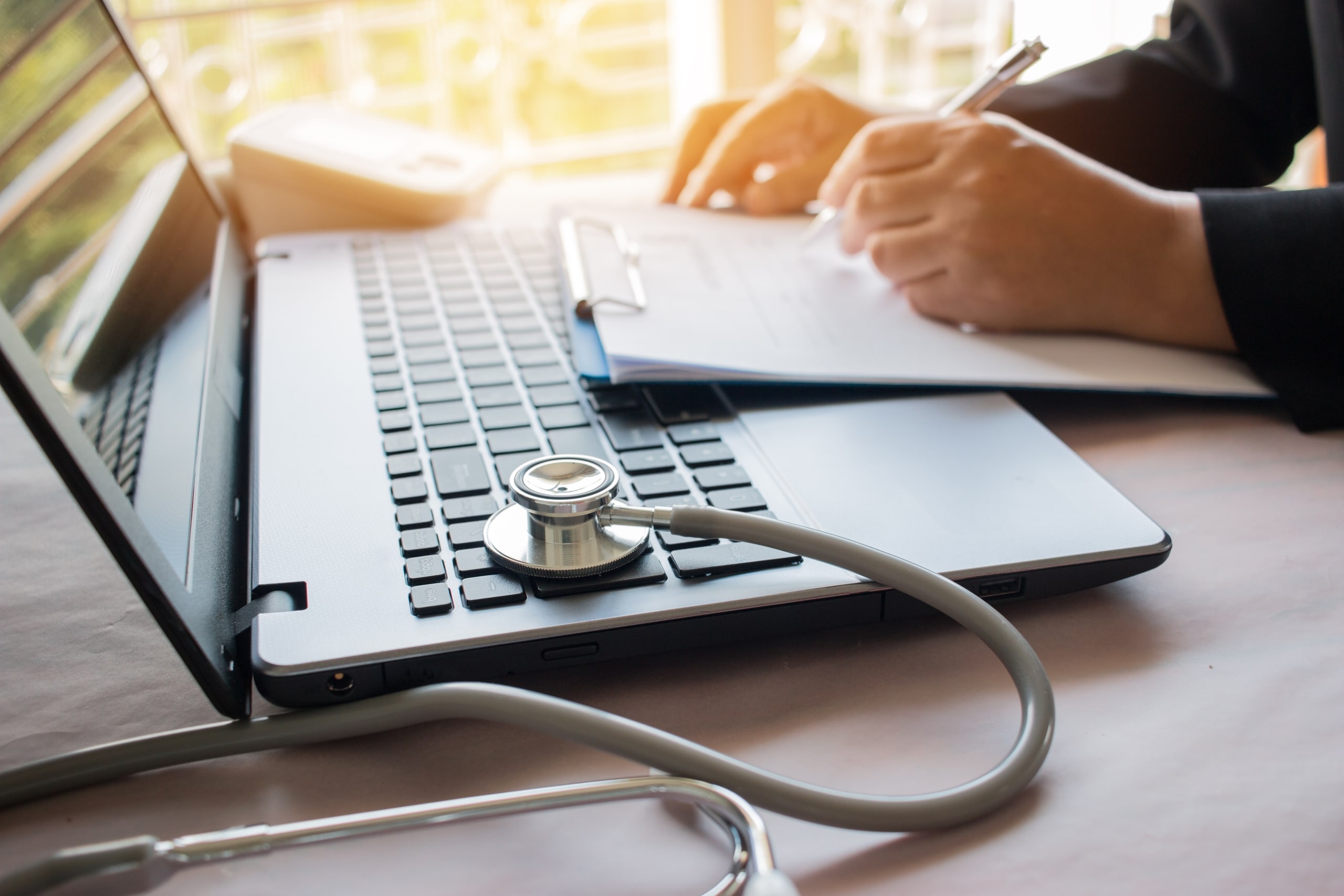 Medical professional using a laptop with a stethoscope on the side